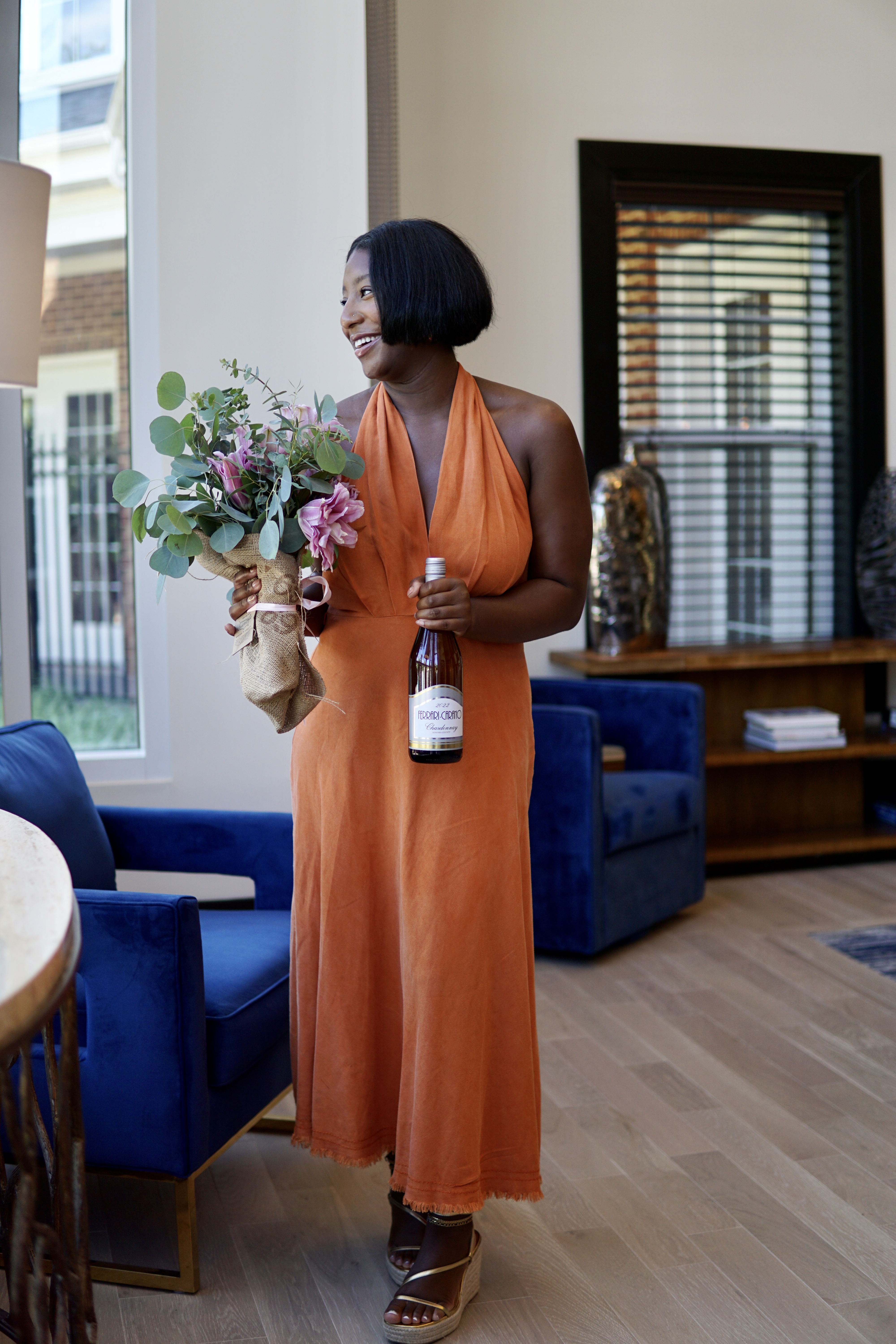 Desiree founder of wino noire holding a bottle of wine and flowers