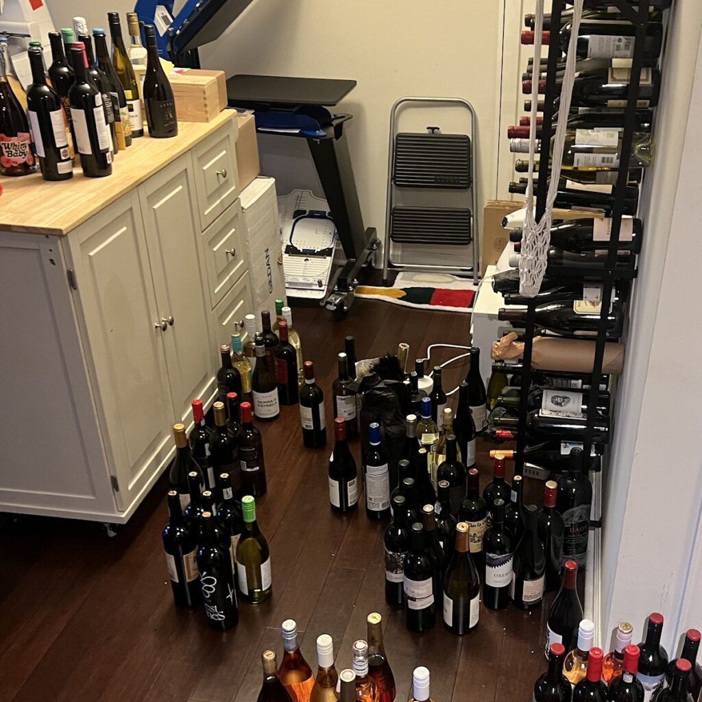 a small room with numerous wine bottles scattered on the floor, creating a disorganized collection